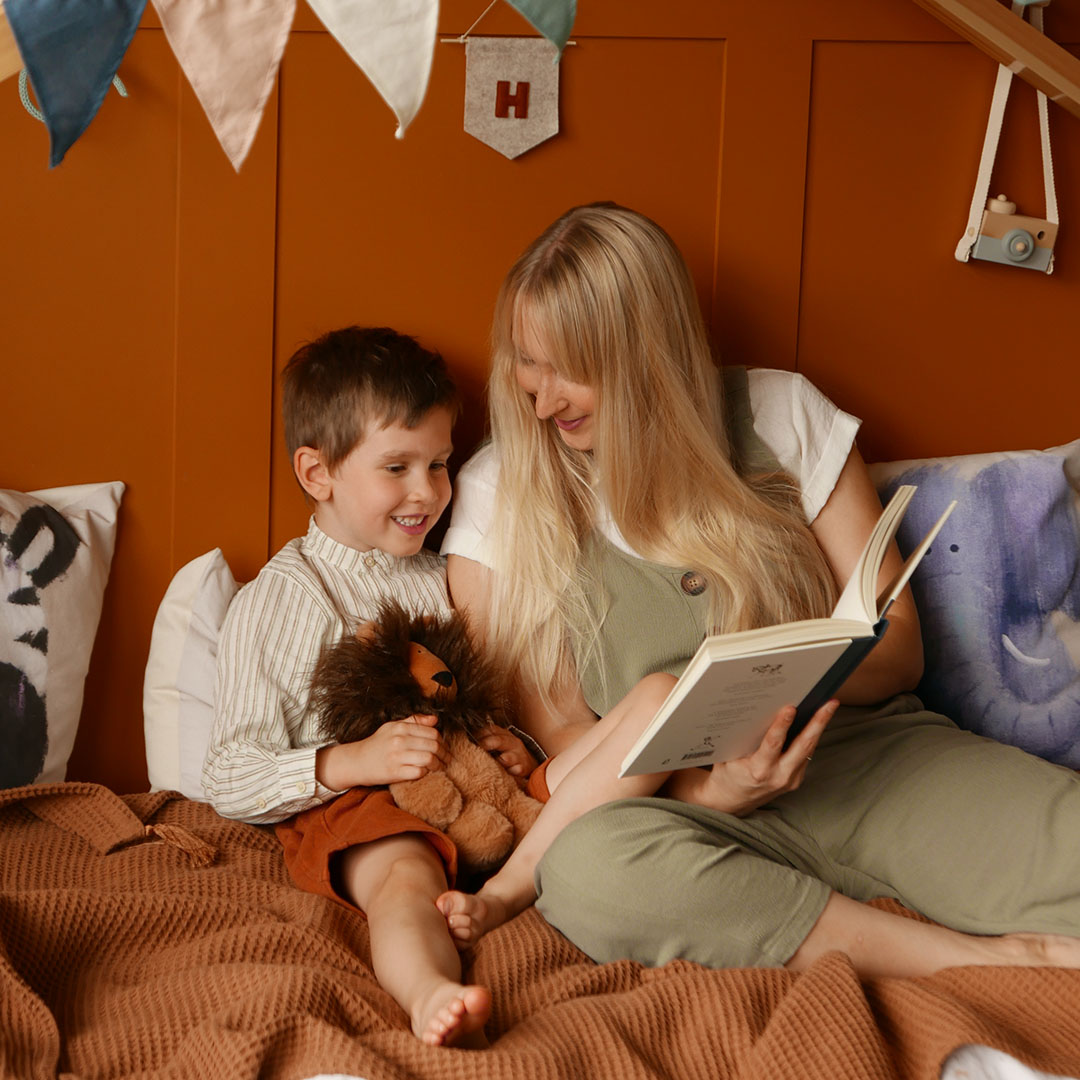 woman reading happy child holding lion soft toy
