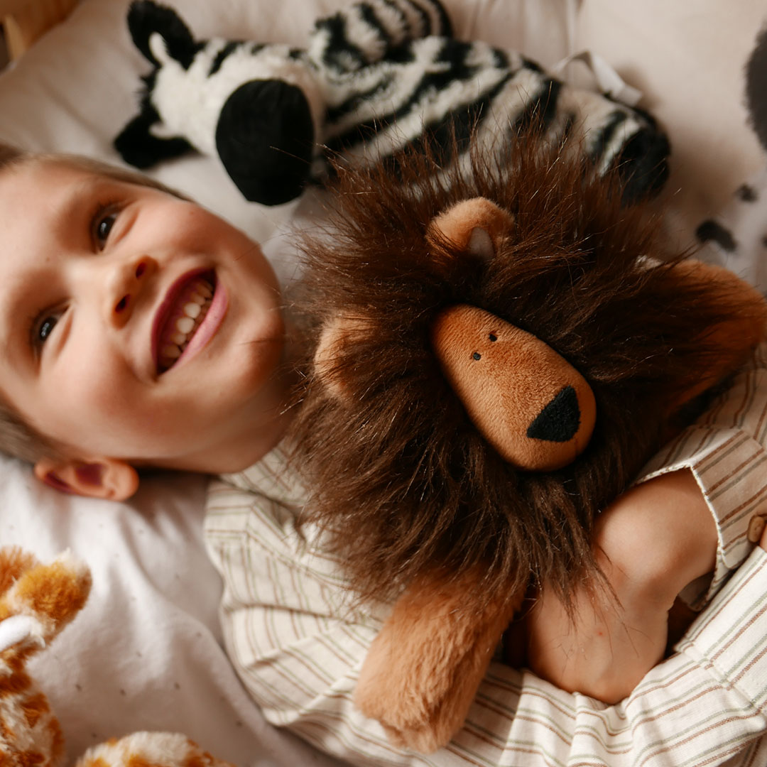 smiling child surrounded by safari soft toys