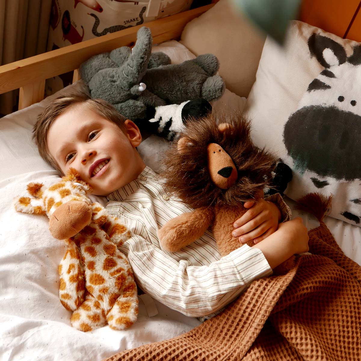 Luxury plush toys, featuring a lion soft toy, a giraffe soft toy, a zebra soft toy and an elephant soft toy next to a zebra cushion cover
